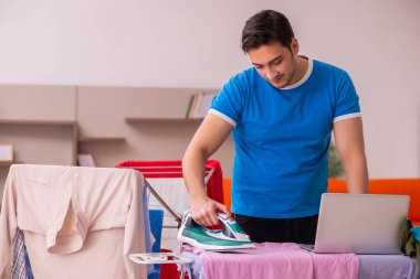 Genç adam evde ütü yapıyor.