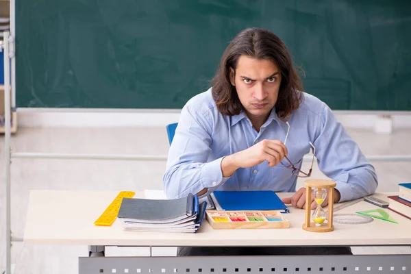 Mladý muž učitel před zelenou tabuli — Stock fotografie