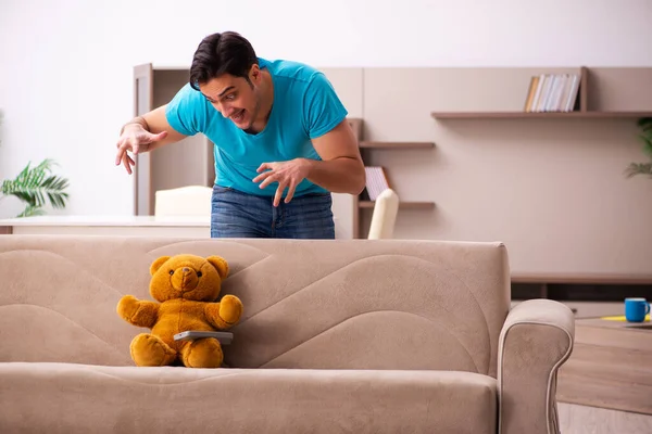 Young man sitting with bear toy at home