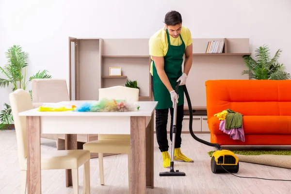 Jovem empreiteiro limpando a casa dentro de casa — Fotografia de Stock