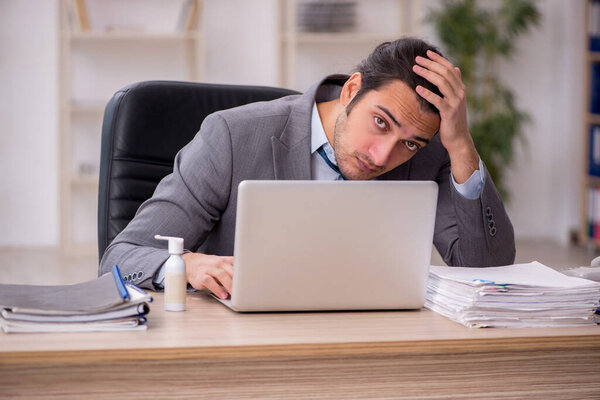 Молодой работник мужчина недоволен чрезмерной работой в офисе