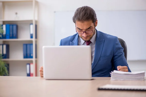 Ung manlig anställd som sitter på kontoret framför whiteboard — Stockfoto