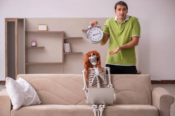 Jeune homme avec squelette féminin dans le concept de gestion du temps — Photo