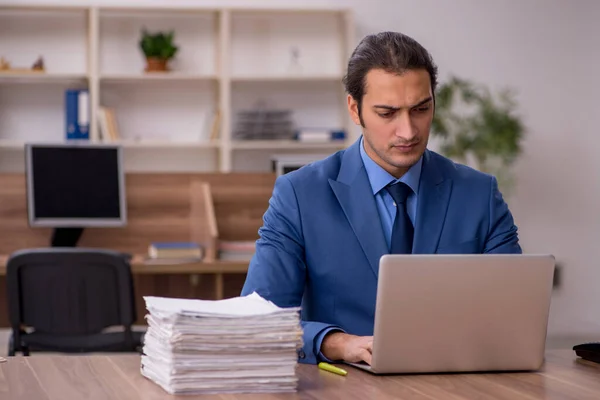 Ung manlig anställd och mycket arbete på kontoret — Stockfoto