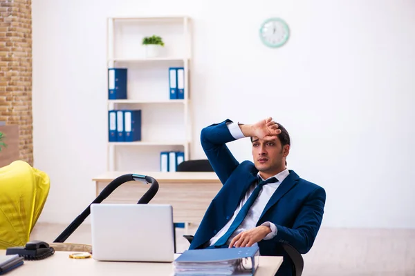 Young male employee looking after kid at workplace — Stock Photo, Image