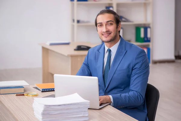 Joven empleado masculino y demasiado trabajo en la oficina — Foto de Stock