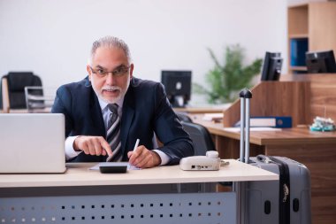 Eski erkek çalışan ofiste seyahat için hazırlanıyor.