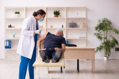 Yaşlı adam covid-19 aşı konseptinde genç doktoru ziyaret ediyor.