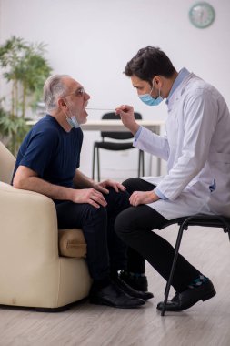 Yaşlı erkek hasta genç doktor otorhinolaryngologis 'i ziyaret ediyor.