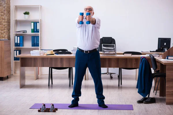 Old businessman employee doing sport exercises in the office — Stock Photo, Image