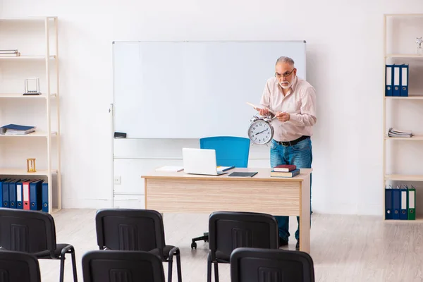Старый учитель мужского пола в классе по концепции управления временем — стоковое фото