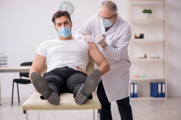 Jeune patient de sexe masculin visitant un vieux médecin en conce de vaccination — Photo