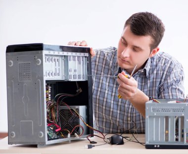 Genç teknisyen atölyede bilgisayar tamir ediyor.