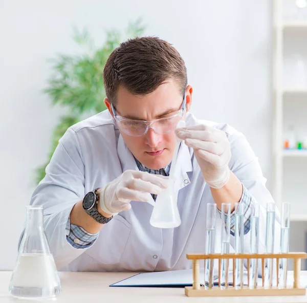 Joven estudiante de química experimentando en laboratorio — Foto de Stock