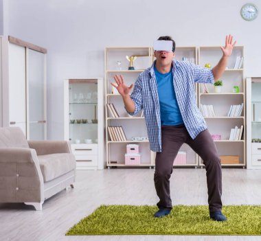 Evde sanal gerçeklik gözlüklü bir adam oynuyor.