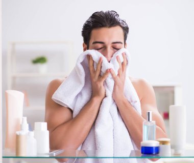 Genç adam banyoda çalışmak için hazırlanıyor.