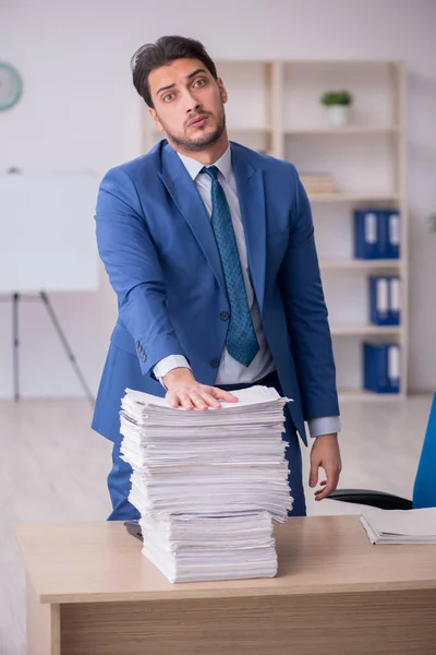 Jonge mannelijke werknemer ongelukkig met overmatig werk in het kantoor — Stockfoto