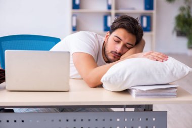 Genç bir erkek işçi yataktan kalkıp işe geliyor.