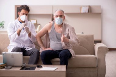 Genç erkek doktor aşı konseptinde yaşlı hastayı ziyaret ediyor.