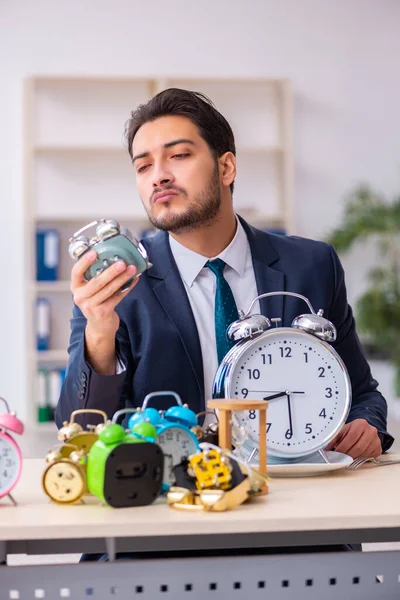目覚まし時計を食べる若いビジネスマンの従業員 — ストック写真
