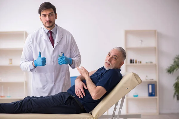 Пациент пожилого возраста посещает молодого врача-мужчину в вакцинации — стоковое фото