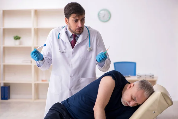 Oude mannelijke patiënt op bezoek bij jonge mannelijke arts in vaccinatiecentrum — Stockfoto