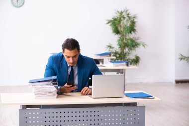 Genç erkek çalışan ofiste oturuyor.