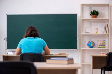 Yeşil panonun önünde genç bir erkek öğrenci.