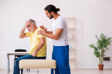 Yaşlı erkek hasta, genç erkek doktor masörünü ziyaret ediyor.