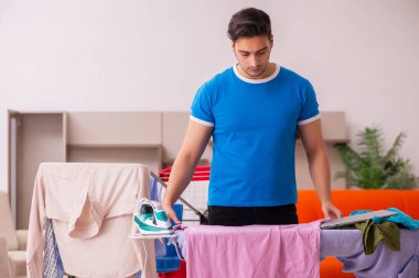 Genç adam evde ütü yapıyor.