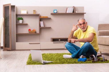 Yaşlı adam evde spor egzersizleri yapıyor.