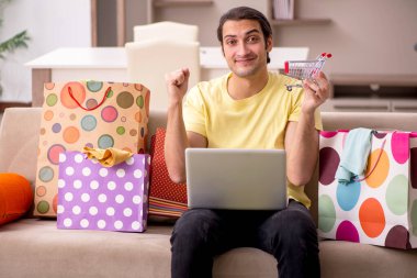 Evde bir sürü çantası olan genç bir adam var.