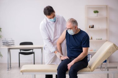 Yaşlı bir erkek hasta aşıyla genç bir doktoru ziyaret ediyor.