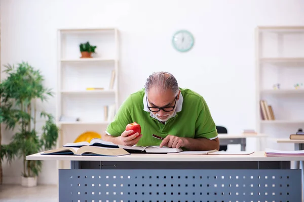 Oude mannelijke student eet appel tijdens de voorbereiding van het examen — Stockfoto