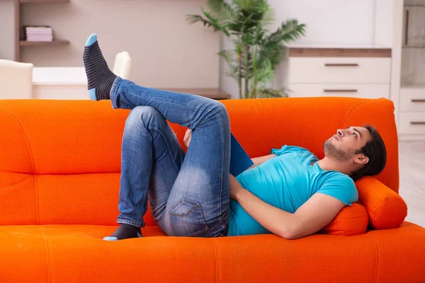 年轻的男生坐在橙色的沙发上 — 图库照片