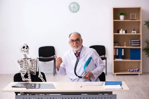 Oude mannelijke dokter en skelet patiënt in de kliniek — Stockfoto