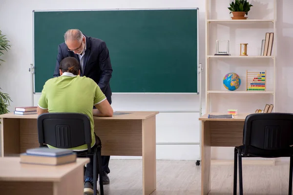 Profesor de edad y joven estudiante masculino en el aula — Foto de Stock