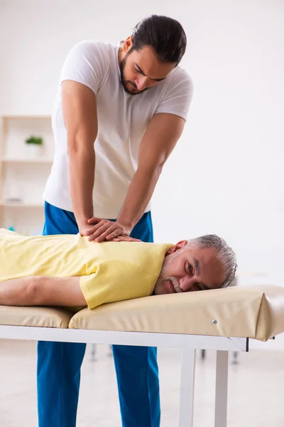 Starý mužský pacient návštěva mladý mužský lékař chiropraktik — Stock fotografie