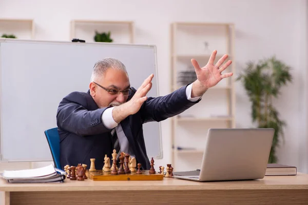 Starý muž zaměstnanec hraje šachy na pracovišti — Stock fotografie