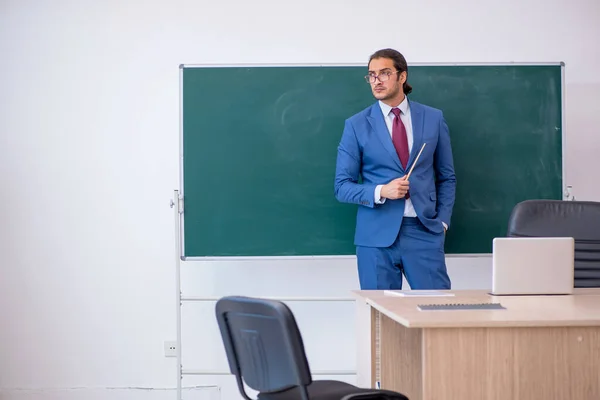 Joven profesor de traje delante del tablero verde —  Fotos de Stock