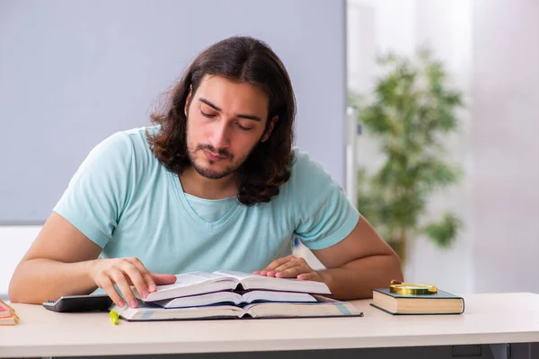 Ung manlig student förbereder sig för tentor i klassrummet — Stockfoto