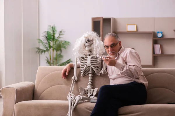 Old man sitting on the sofa with the female skeleton — Stock Photo, Image