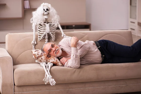 Alter Mann sitzt auf dem Sofa mit dem weiblichen Skelett — Stockfoto