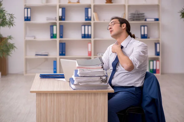 Junge männliche Mitarbeiter und viel Arbeit im Büro — Stockfoto