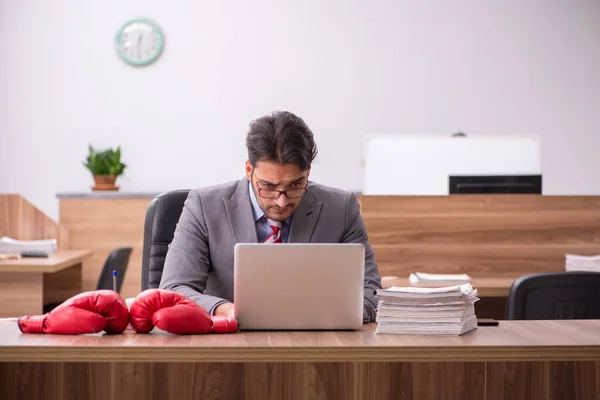 Junge männliche Angestellte trägt am Arbeitsplatz Boxhandschuhe — Stockfoto