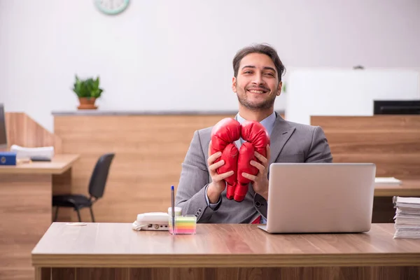 Joven empleado masculino usando guantes de boxeo en el lugar de trabajo —  Fotos de Stock