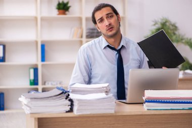 Genç bir erkek çalışan ve ofiste çok fazla iş var.