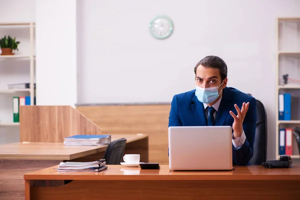 Jeune employé masculin travaillant dans le bureau portant un masque — Photo