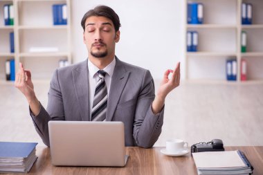 Genç çekici erkek çalışan işyerinde oturuyor.