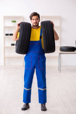 Atölyede lastiği olan genç bir erkek tamirci.